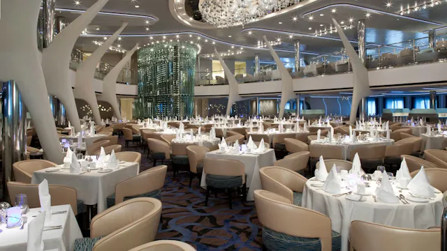 Groot restaurant op een cruiseschip met elegante tafels, witte tafelkleden, sfeervolle verlichting en moderne architectuur.