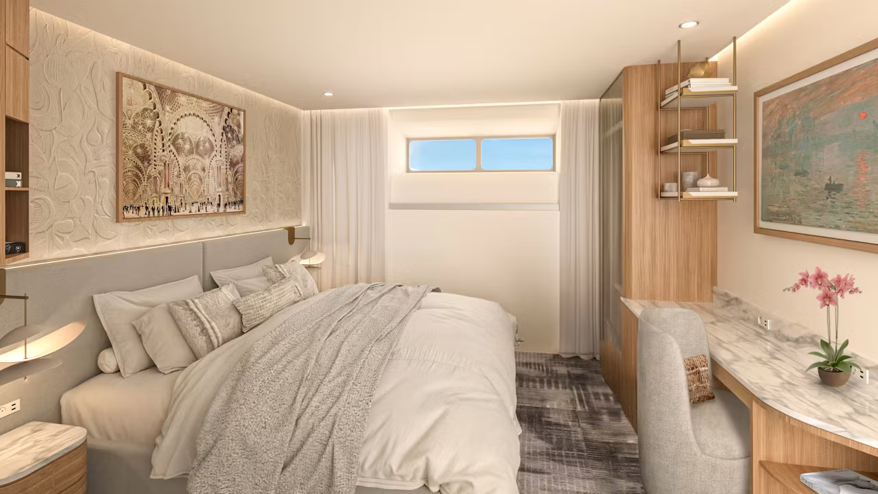 Moderne hut aan boord van een Celebrity Cruises schip met comfortabel tweepersoonsbed, bureau en stijlvolle inrichting.