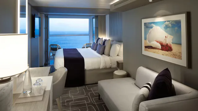 Moderne cruisehut met tweepersoonsbed, zithoek en open balkon met uitzicht op zee.