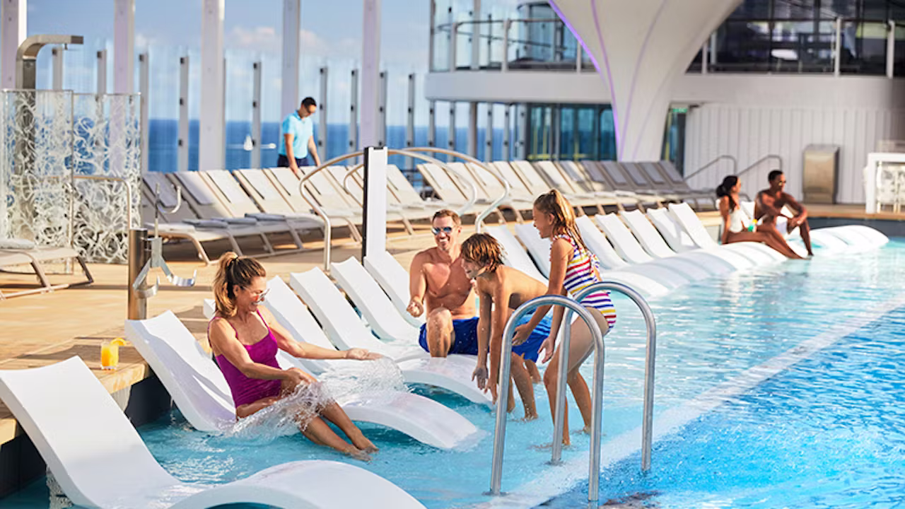Gezin dat ontspant en speelt in het zwembad op het zonnedek van een cruiseschip met ligstoelen langs het water. 