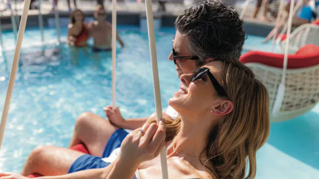 Koppel dat ontspant op een hangstoel bij het zwembad op het zonnedek van een cruiseschip.