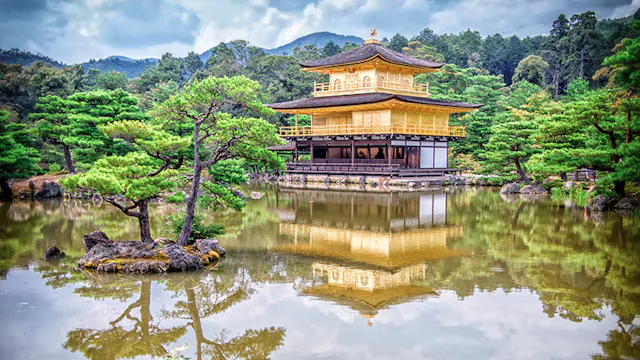 Traditionele Japanse tempel aan het water, omringd door natuur met weerspiegeling in het meer.